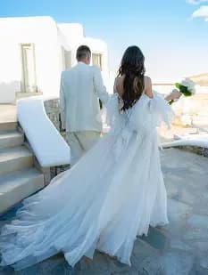 Bride and groom walking hand in hand by the sea.