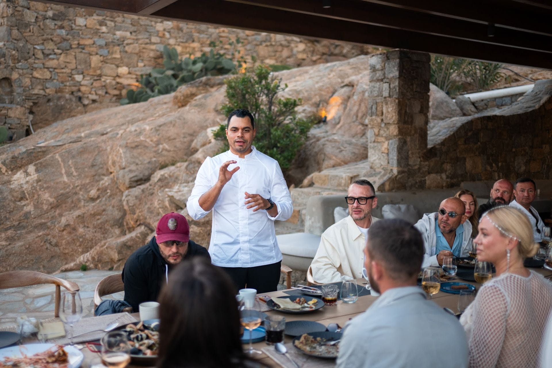 Private chef speaking with guests at an outdoor dinner table