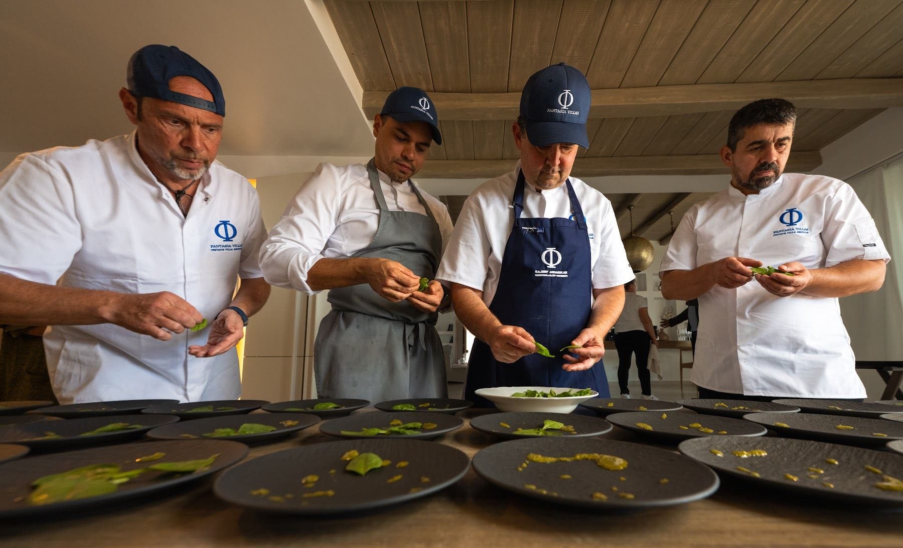 Four Fantasia chefs finishing a line of black plates