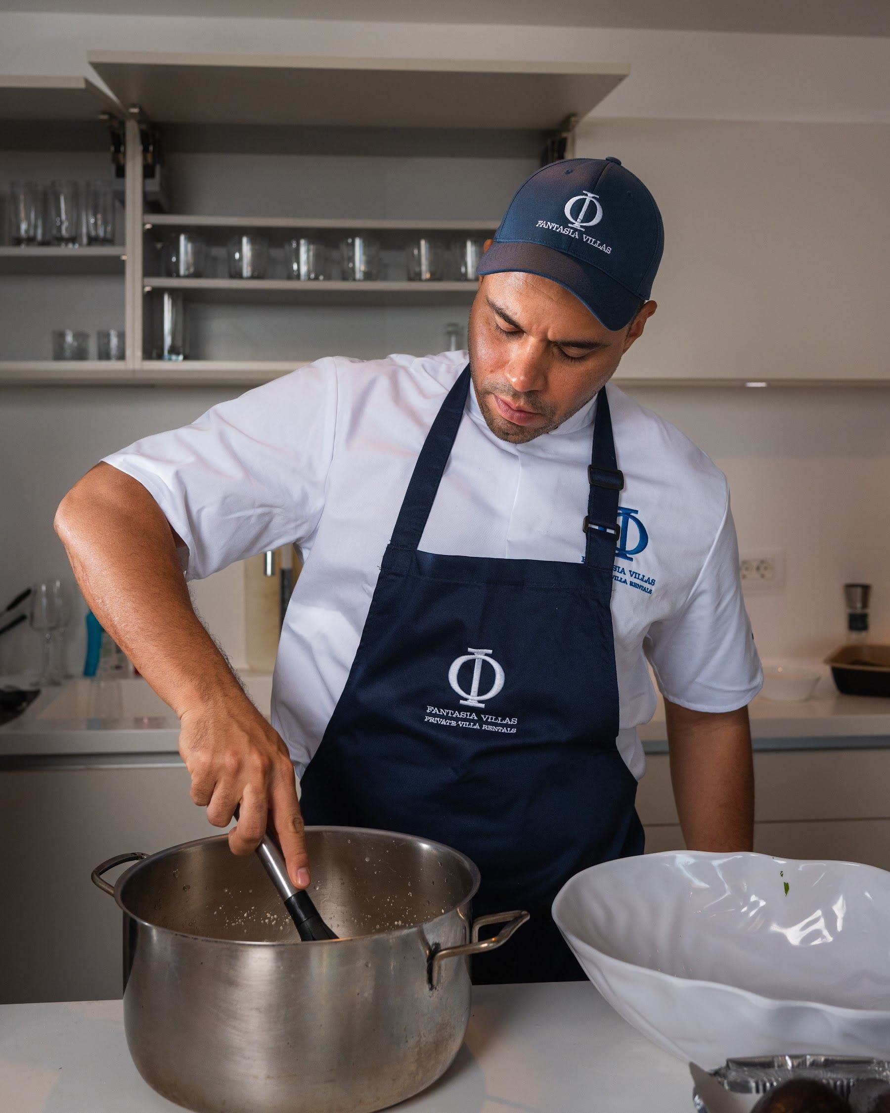 Private chef in Fantasia uniform whisking at the villa kitchen