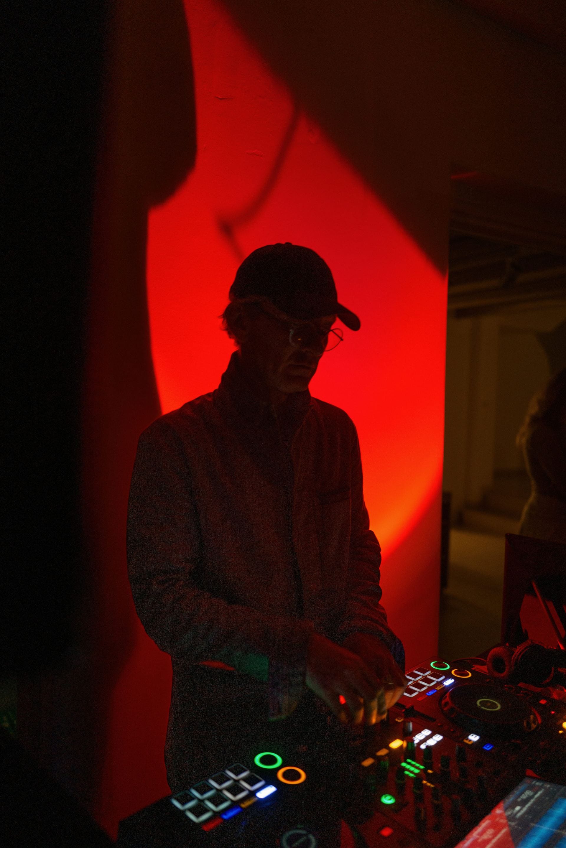 DJ performing under red lighting at a private event.