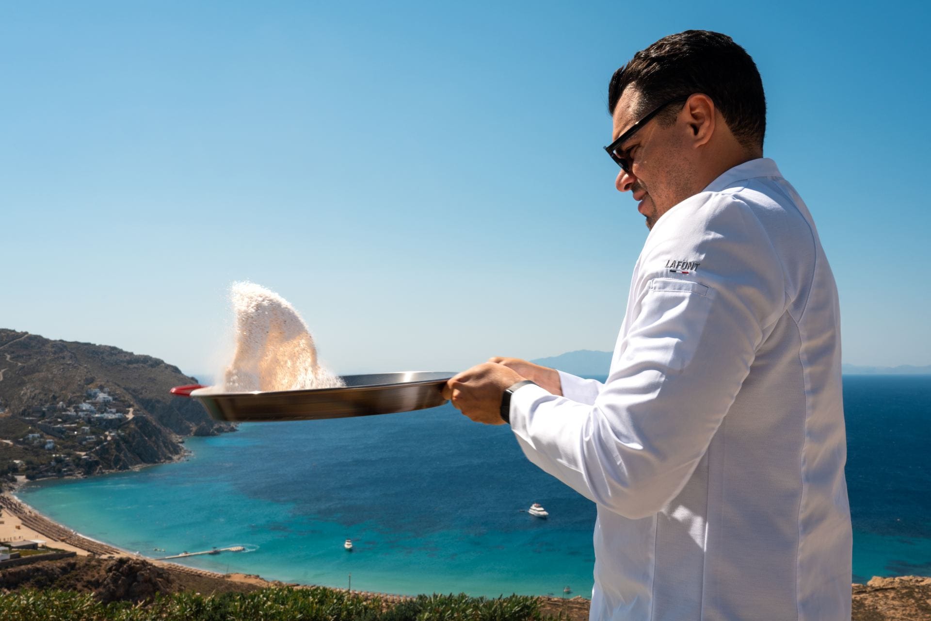 Private chef preparing a dish against sweeping turquoise sea views.