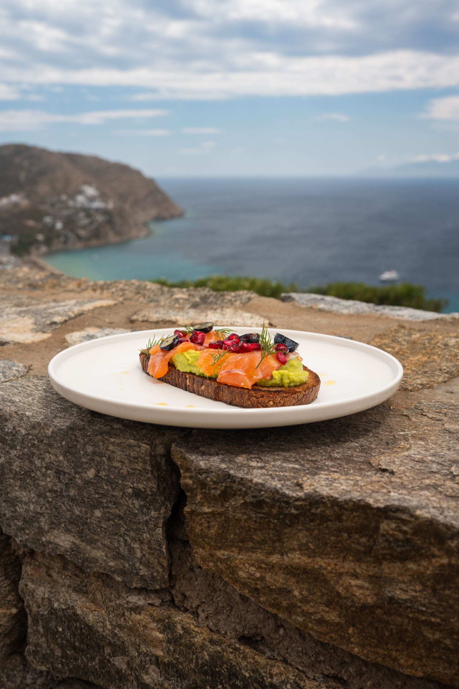 Smoked salmon and avocado toast served against sweeping sea views.