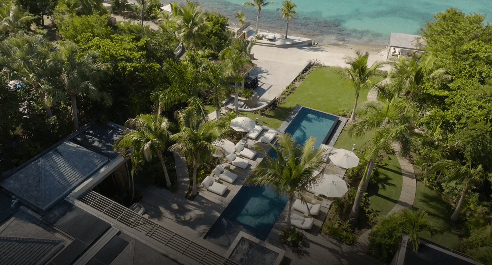 Luxury beachfront villa with pool, lush tropical gardens, and direct access to a sandy beach.